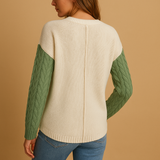 Knitted women's sweater with cable pattern and pocket detail.